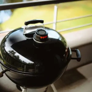 herQs Kuppelthermometer, montiert an einem schwarzen Kugelgrill zur Temperaturüberwachung beim Grillen im Freien