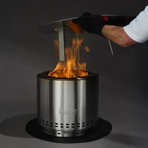 herQs Cozy Heater iš šlifuoto plieno, su liepsna ir mūvėta pirštine ranka, reguliuojančia viršutinę dalį ant tamsaus pagrindo