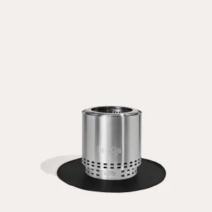 herQs Cozy & Blaze tapis chauffant présenté comme une base cylindrique en métal brossé sur un tapis circulaire noir