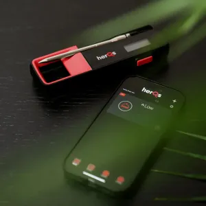herQs Single Max trådlös grilltermometer med sond bredvid en smartphone som visar appen