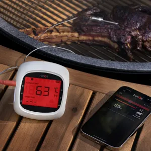herQs EasyBBQ trådlös köttermometer med appaviseringar, som visar temperaturen på displayen bredvid grillen