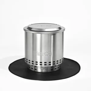herQs Cozy fire pit lid in brushed silver metal with embossed logo, shown on a black mat