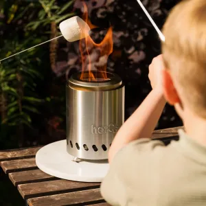 herQs smokeless tabletop fire pit burning on a wooden table, with a marshmallow skewer over the flame