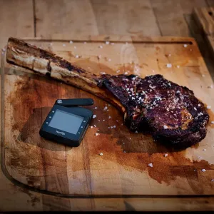 herQs Professional kabelloses Thermometer neben einem gegarten Tomahawk-Steak auf einem Holzschneidebrett