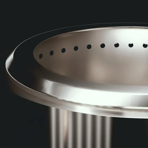 herQs Blaze eldstad i rostfritt stål, närbild av övre kant med rundad läpp och rad ventilationshål på insidan, mörk bakgrund.