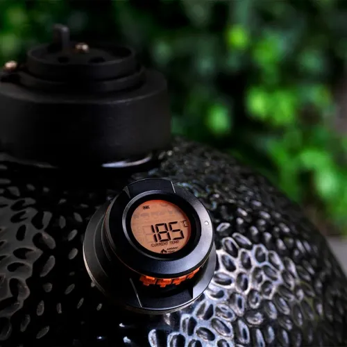 HerQs Dome BBQ-termometer i svart, rund med orange bakbelyst LCD-display och knappar, monterad på texturerad grillkupol.