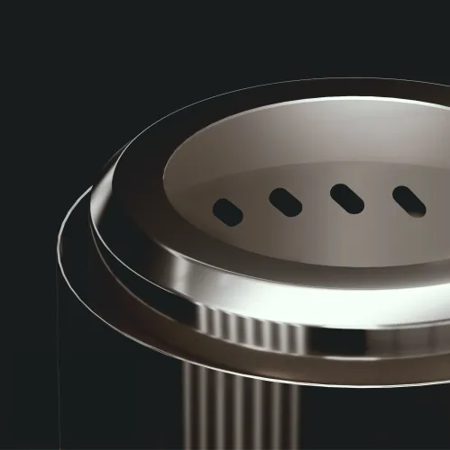 Kompakti savuton ruostumattomasta teräksestä valmistettu takka, lähikuva yläreunasta, jossa on pyöristetty reunaprofiili ja neljä soikeaa tuuletusreikää yläreunassa.